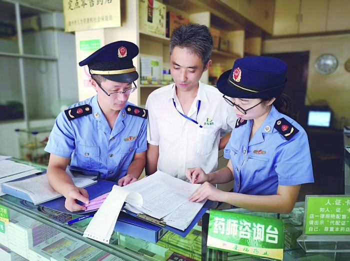 執法人員在一家藥店檢查特殊藥品進貨臺賬。