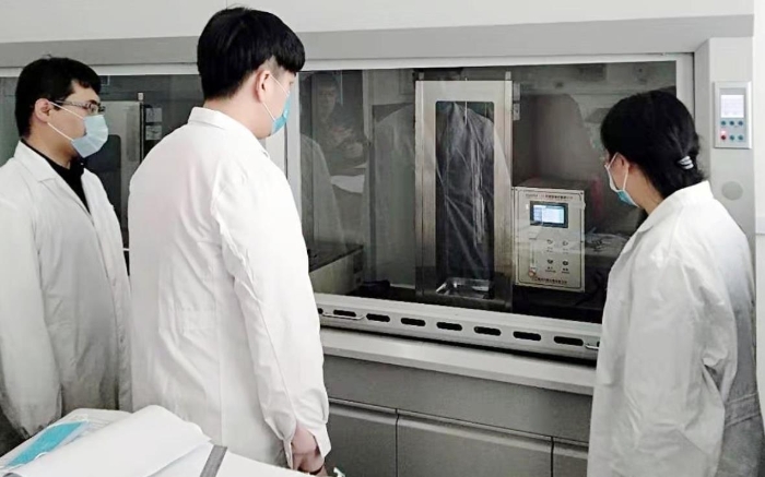 圖為吉林器械所檢驗人員開展疫情防護用品的阻燃試驗。