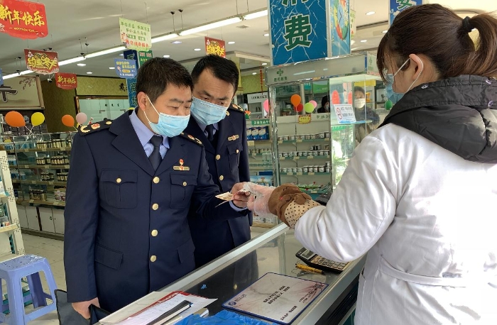 執法人員在一家藥店檢查口罩質量和進銷價單據