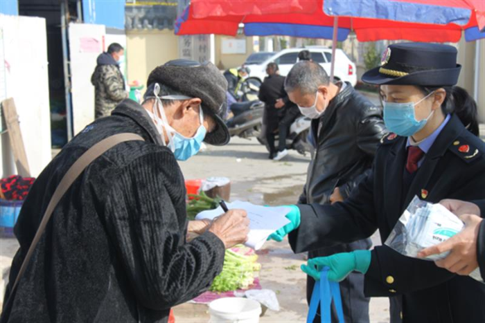 圖為鷹潭市市場監管局工作人員向經營戶發放口罩。