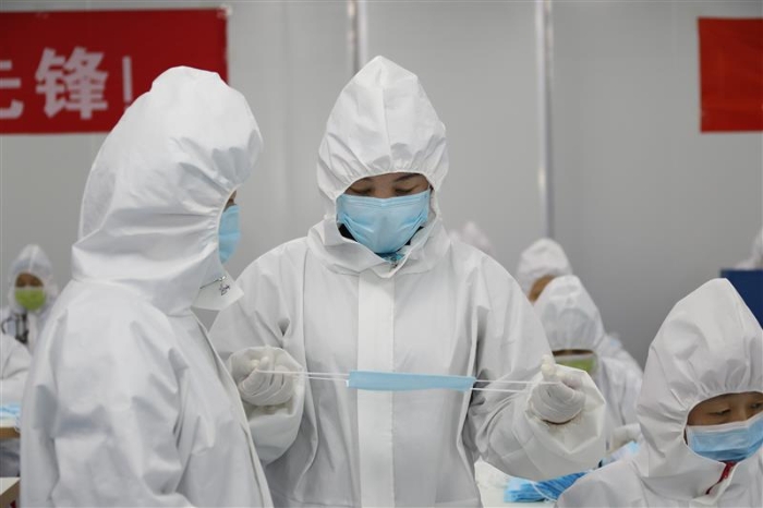 新疆維吾爾自治區藥監局駐企特派員馬小華（右）正在與企業質量負責人溝通口罩生產中遇到的問題。（馬少賓 攝）