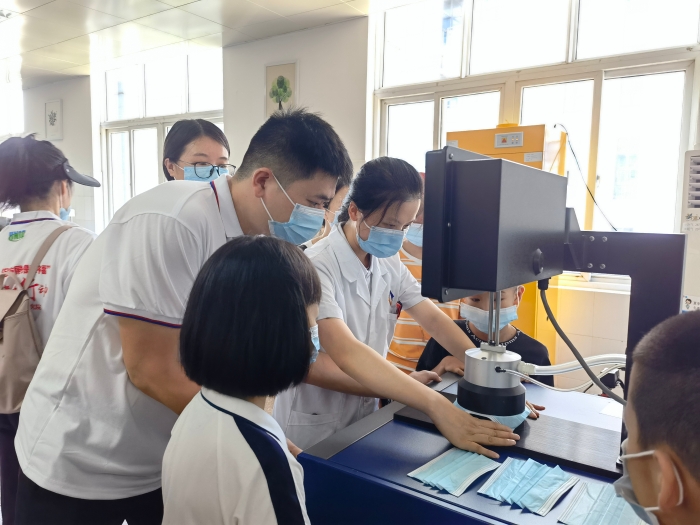 圖為技術人員在講解口罩的檢驗方法和原理。（喻燦華 攝）