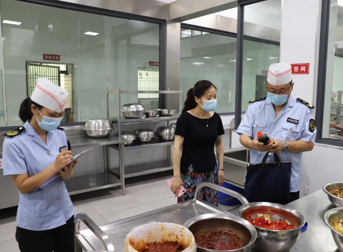 圖為執法人員在檢查學校食堂加工制作情況。