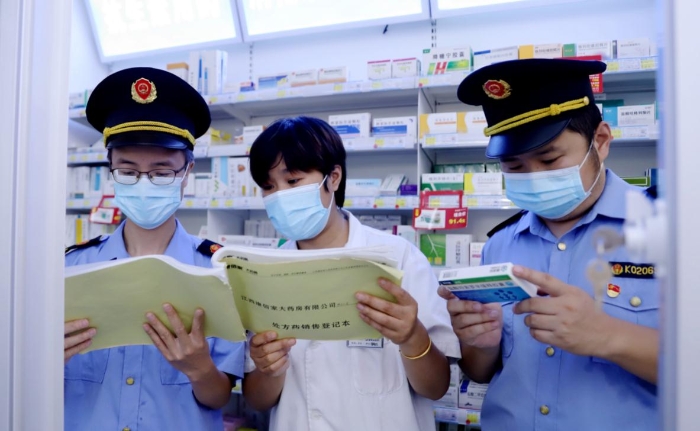 執法人員查看藥店網絡藥品銷售登記并核對處方藥處方單