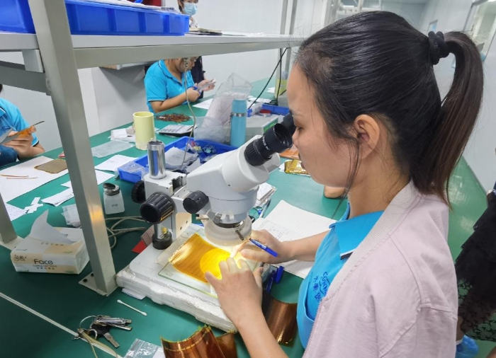 開蒙醫(yī)療員工在用顯微鏡檢查人體成分分析儀芯片上的箔片集成電路是否有缺陷。