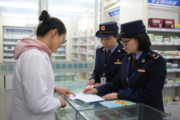 圖為執法人員在佰藥之家大藥房發放安全用藥科普手冊。