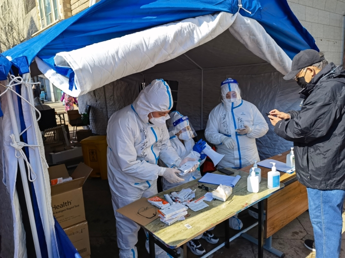 圖為吉林省藥監局黨員干部在社區發放新冠抗原檢測試劑盒