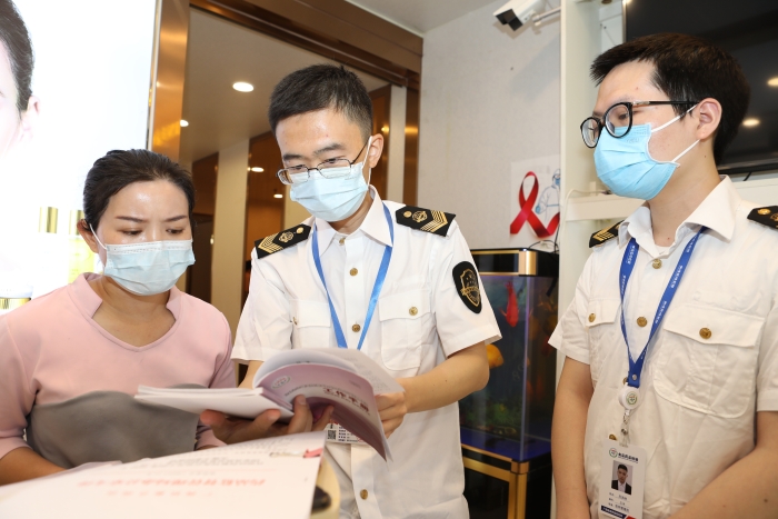 圖為抽檢人員向經營者宣貫化妝品監管法規文件。