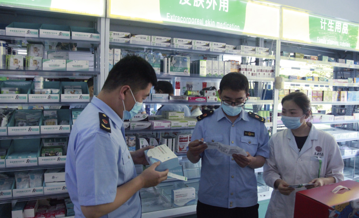 圖為青州市市場監管局執法人員在一家藥店檢查抗原檢測試劑盒質量。