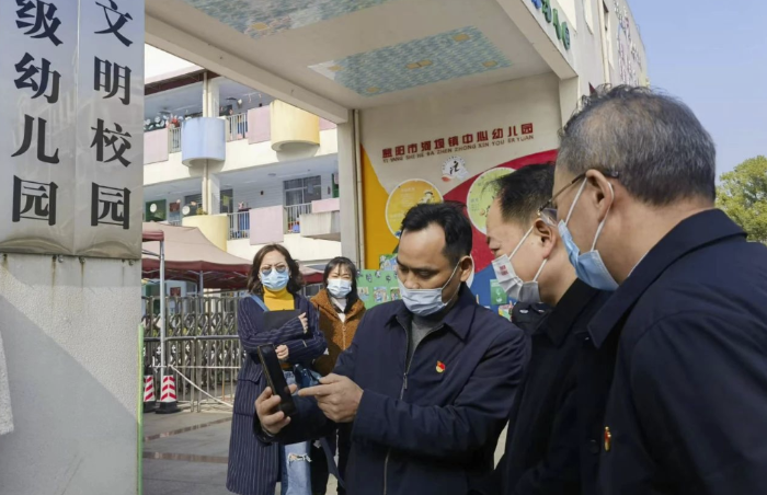 圖為樂運(yùn)成（右二）通過(guò)手機(jī)客戶端查看大通湖區(qū)第一實(shí)驗(yàn)幼兒園廚房實(shí)時(shí)視頻。