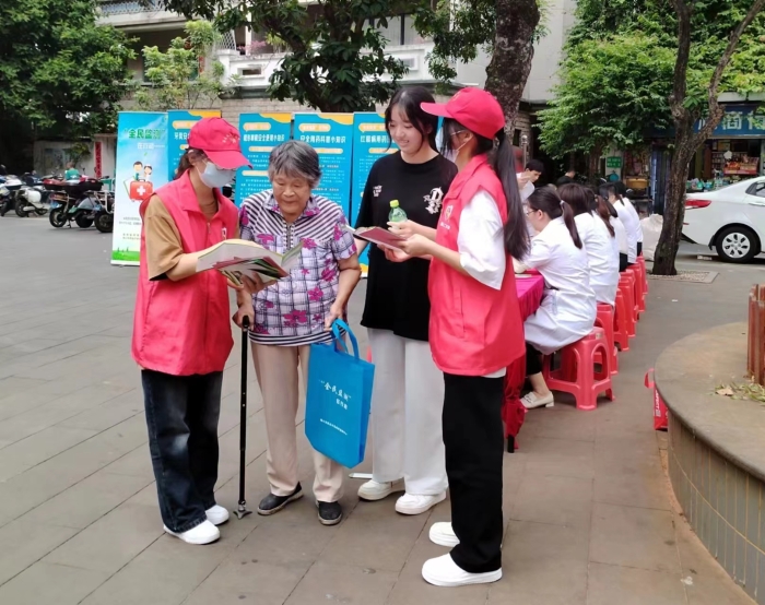 圖為工作人員向過往居民發放“全民監測”科普宣傳資料。